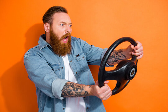 Photo of young stupor funny man wear jeans denim jacket hold steering wheel broken car prohibition road accident isolated on orange color background