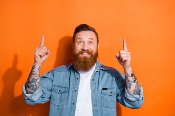 Photo of positive extravagant man look indicate fingers up empty space isolated on orange color background