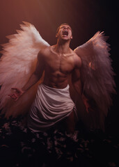 Young strong angel with white wings from heaven. Angel with muscular body. Sensual man