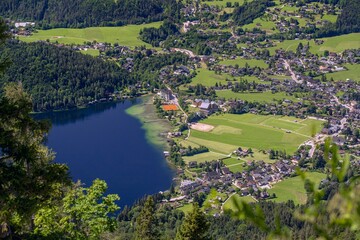 Fototapeta premium Idyllic landscape of a mountain range with rolling, verdant hills, lush green trees, and a lake