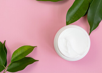 Open cream with green leaf on background. Organic skin care concept Clear cosmetic cream, face serum, moisturizer background. top view.