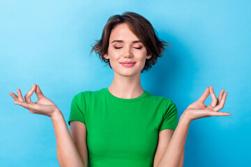 Photo of sweet dreamy woman wear green t-shirt closed eyes enjoying yoga smiling isolated blue...