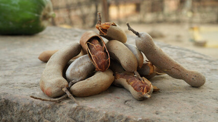 top view of Pile ripe Tamarind fruits Sweet tamarinds tropical fruit with leaf isolated Delicious on black wooden table flat lay
