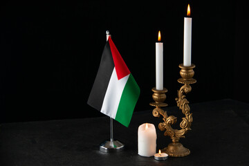 front view of burning candles with palestinian flag on dark floor funeral death israel