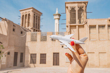 Hand with toy airplane in old town Bur Dubai or Al Fahidi district. Air transport ticket prices and travel concept.