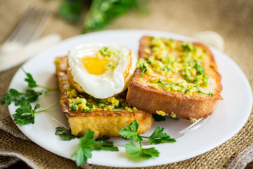 Fried croutons in batter with garlic and herbs and a fried egg in a plate.