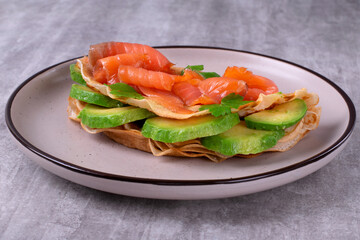 Crepe with salted trout and avocado on ceramic plate. Breakfast meal