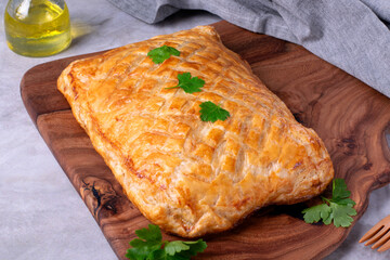 Puff pastry pie with filling served on wooden board - 594682663