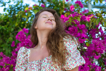 Portrait of happy beautiful girl, young positive woman is smelling beautiful pink flowers in the...