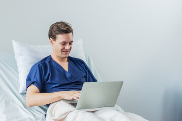 Caucasian patient using laptop in hospital room. man sick patient lying in a hospital bed