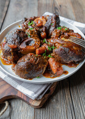 Braised beef shanks with gravy on a plate isolated on wooden table 
