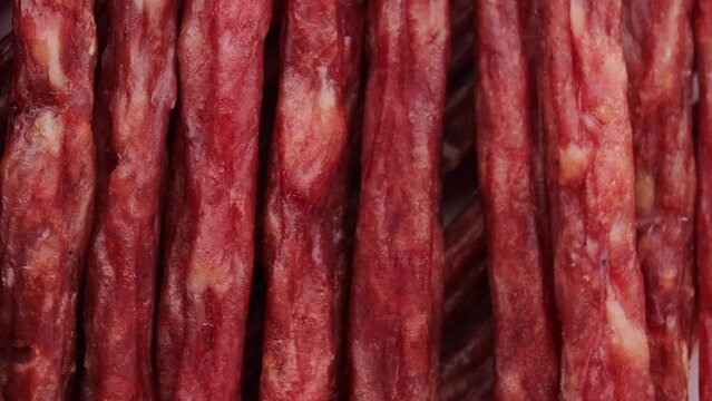 dried meat in the form of thin sausages, rotation in circle. meat beer snack Turning. selective focus. macro