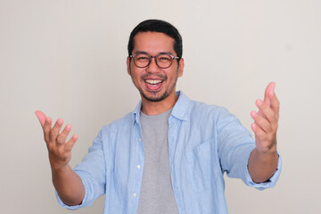 Adult Asian man looking camera showing excited expression with both hands want to embrace someone
