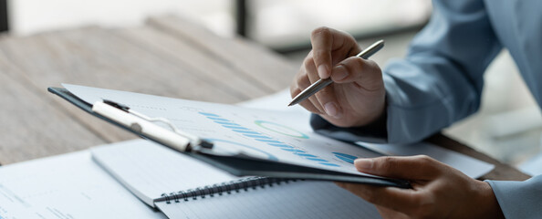 Asian businesswoman, investor, insurance salesman looking with pen pointing at data sheet on...