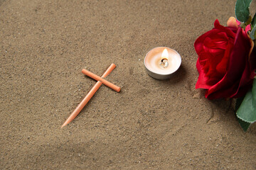 front view of stick cross with red flowers on the sand palestine funeral death israel
