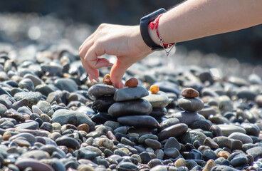 A woman builds a cairn on the beach
