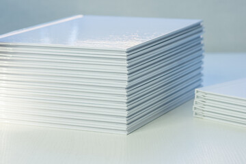 stacks of freshly printed photobooks with clean white covers on the table close-up