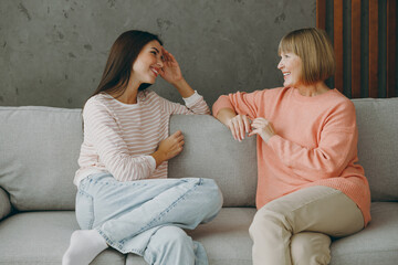 Two adult smiling happy women mature mom young kid wear casual clothes tal speak together hug sit...