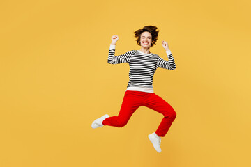 Fototapeta na wymiar Full body young woman wear casual black and white shirt jump high doing winner gesture celebrate clenching fists say yes isolated on plain yellow color background studio portrait. Lifestyle concept.