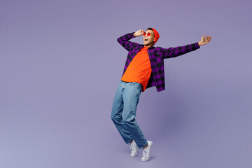 Full body young man of African American ethnicity wear casual shirt orange hat stand on toes leaning back with outstretched hand dance isolated on plain pastel purple color background studio portrait.