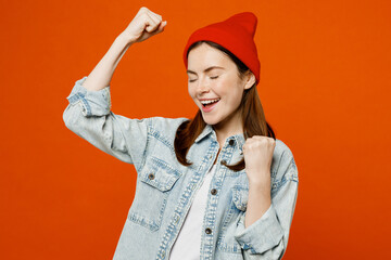 Young smiling cheerful happy woman wear denim shirt white t-shirt red hat doing winner gesture...