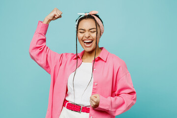 Young fun woman of African American ethnicity wear pink shirt white t-shirt headscarf doing winner gesture celebrate clenching fists say yes isolated on plain pastel light blue cyan background studio. - obrazy, fototapety, plakaty