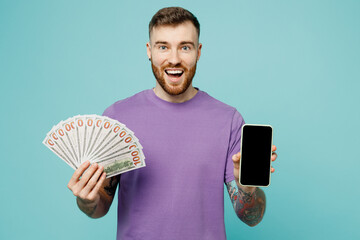 Young man he wears purple t-shirt hold fan of cash money in dollar banknotes use mobile cell phone...