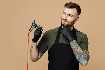 Minded thoughtful tattooer master artist tattooed man wear green t-shirt apron prop up chin hold...