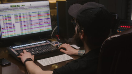 Musical band records song in music recording room. Audio engineer or producer uses computer with professional software and DAW controller for creating music. Sound recording studio. Music production.