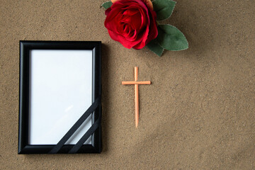 top view of stick cross with red flower and picture frame on the sand death funeral palestine