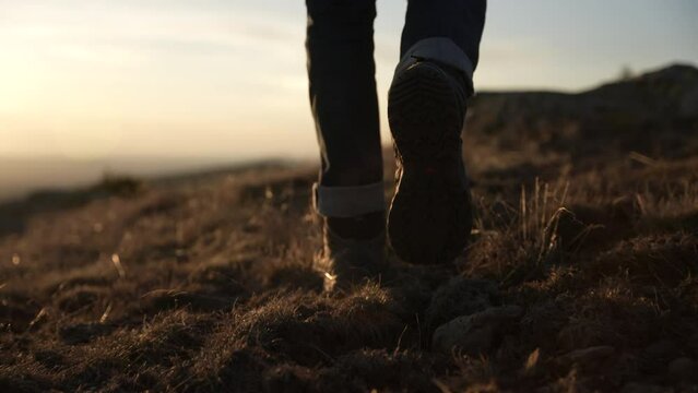 Shot of feet in boots walking along a path at sunset