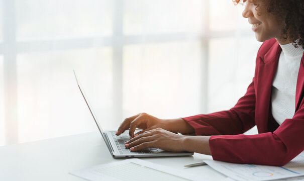 African american businesswoman sitting and recording data details in financial business Online marketing plan to process and send emails for meeting preparation sitting at laptop desk in office.