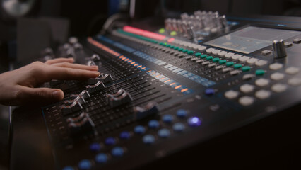 Audio engineer uses mixing console, remote control for adjusting sound, audio mixer. Musician...