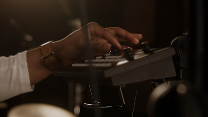 Close up shot of African American singer using audio mixer in soundproof room. Professional tools for creating music in sound recording studio. Remote control for adjusting sound. Music production.