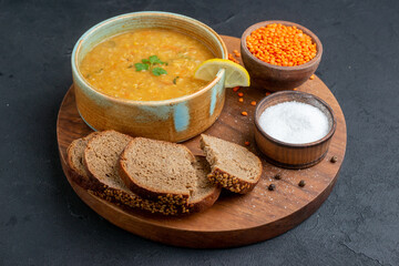 front view lentil soup with salt raw lentils and dark bread loafs on dark surface diner dinner bread horizontal dish food colourful meal