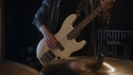 Obraz premium Professional musicians records song in sound recording studio. Male guitarist plays the electric guitar. Close up of drummer playing a drum kit. Work in music recording room. Music production concept.