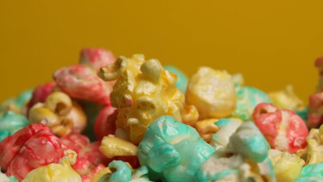 Colored popcorn on a yellow background, rotation in circle. Close-up of Sweet popcorn, top view. popcorn flies in a pile
