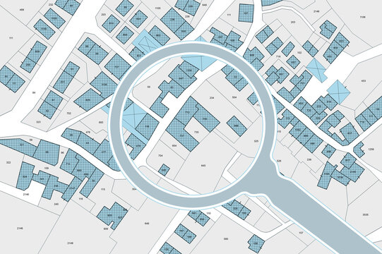 Imaginary cadastral map with buildings, land parcel and vacant plot - property registry and real estate concept seen through a magnifying glass