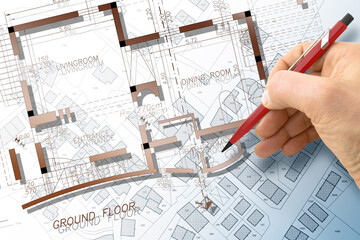 Architect drawing a residential building project over an imaginary cadastral map of territory with buildings and land plots