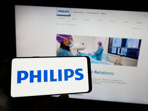 Stuttgart, Germany - 04-16-2023: Person holding mobile phone with logo of Dutch company Koninklijke Philips N.V. on screen in front of business web page. Focus on phone display.