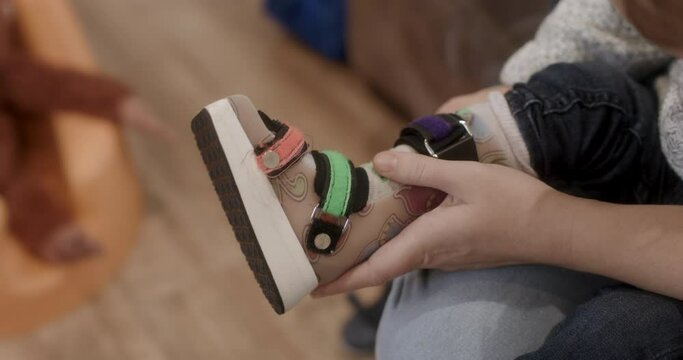 CU Mother putting leg brace on son (18-23 months)