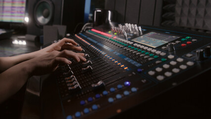 Audio engineer uses mixing console, remote control for adjusting sound, audio mixer. Musician...