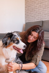 Young woman combing her female dog's hair on the floor. Copy space.