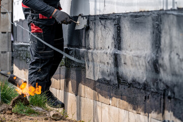waterproofing of the wall with a covered asphalt belt during the construction of the house