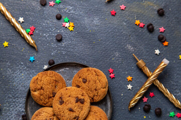 top close view yummy chocolate cookies inside plate with colorful little star signs and candles on the dark-grey desk cookie biscuit sweet tea