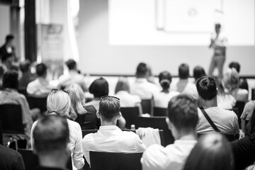Speaker giving a talk in conference hall at business event. Focus on unrecognizable people in...