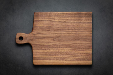 Walnut wood cutting board. A handcrafted black walnut wood chopping board sits on a dark-toned...