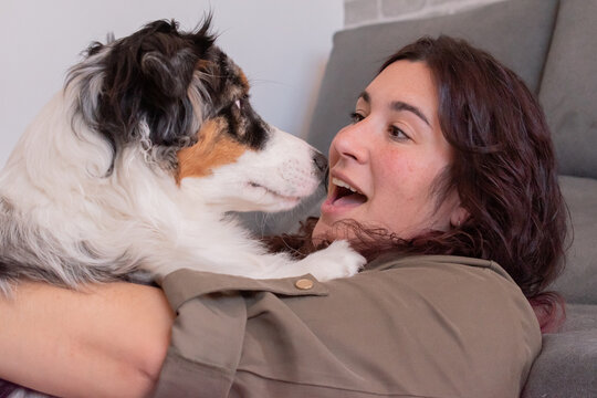 Young woman with a shocked face hugging her dog.