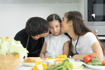 family activities together during the holidays. Father and mother kissing daughter , Parents and children are having activity on vacant time. weekend, enjoyment, happy, togetherness, feel good.