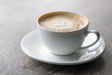Cup of hot cappuccino coffee on table